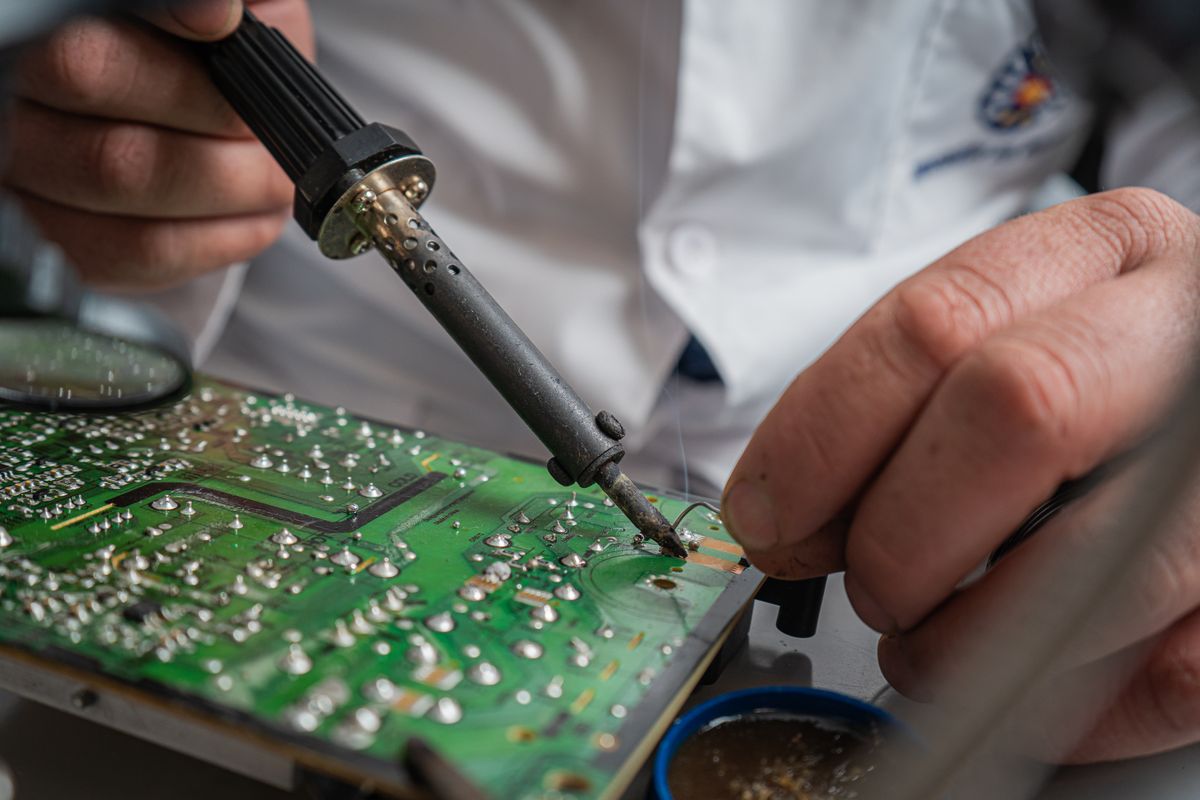 Hands soldering components on a large electronic circuit board