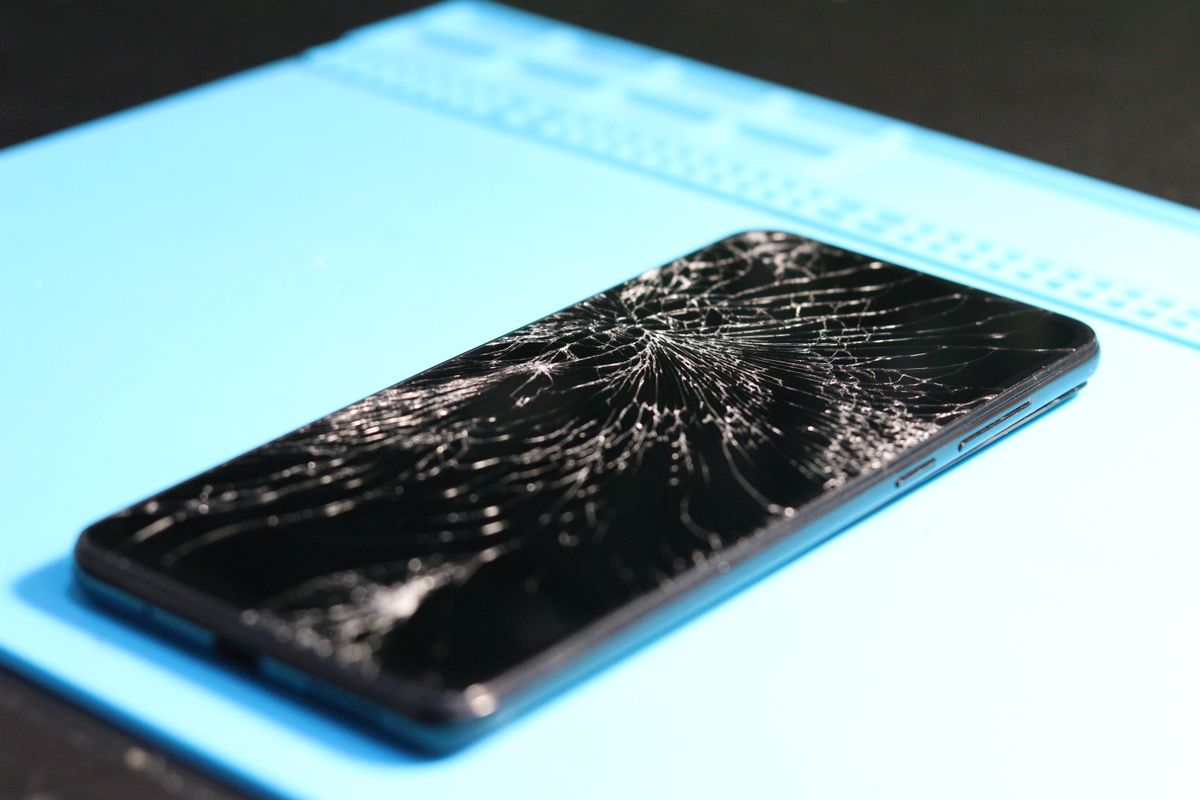 Smartphone with a shattered screen on a repair mat